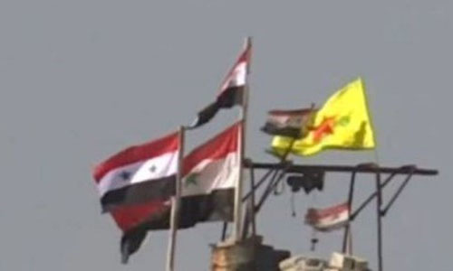 bandera nacional siria junto a la bandera kurda en Manbej